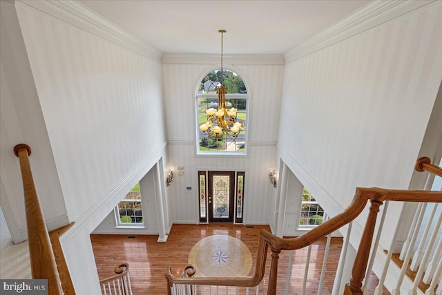 foyer featuring a towering ceiling, a chandelier, hardwood / wood-style flooring, and crown molding