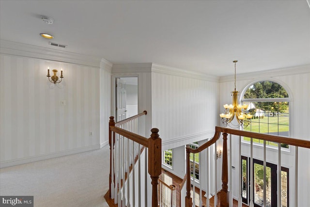 hallway with carpet floors, a notable chandelier, and ornamental molding