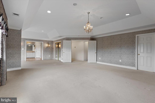 unfurnished living room with a notable chandelier, a tray ceiling, light colored carpet, and ornamental molding