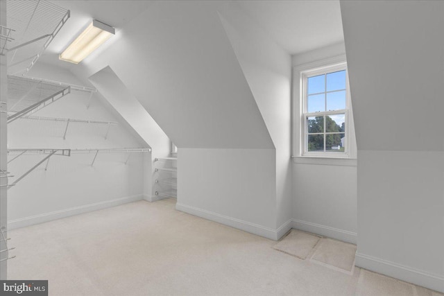 interior space with vaulted ceiling and light colored carpet