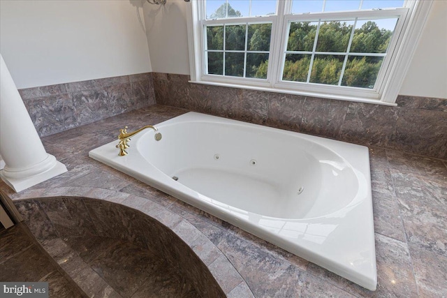 bathroom with decorative columns and tiled bath