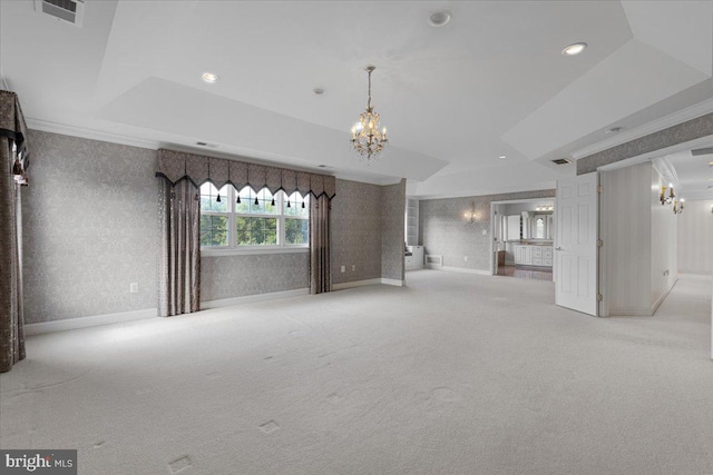 unfurnished living room featuring light carpet, a notable chandelier, a tray ceiling, and crown molding