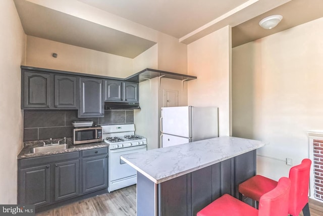 kitchen with light wood-type flooring, backsplash, sink, and white appliances