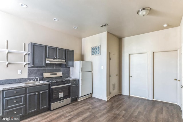 kitchen with tasteful backsplash, white refrigerator, dark hardwood / wood-style flooring, stainless steel range with gas cooktop, and sink