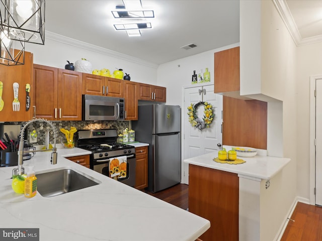 kitchen with ornamental molding, sink, kitchen peninsula, dark wood-type flooring, and stainless steel appliances