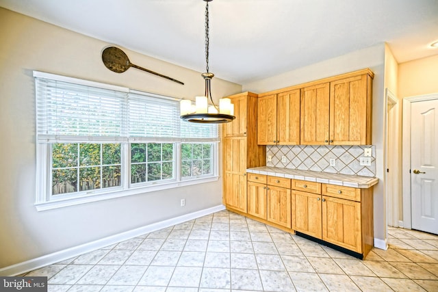 kitchen with pendant lighting, a chandelier, decorative backsplash, tile countertops, and light tile patterned floors