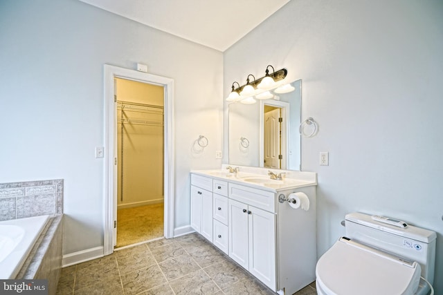 bathroom featuring tiled tub, vanity, and toilet