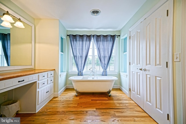 bathroom featuring wood-type flooring, vanity, and a tub to relax in