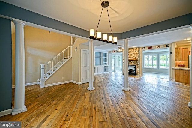 unfurnished living room with hardwood / wood-style flooring, a fireplace, and decorative columns