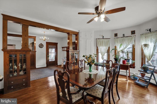 dining area with ceiling fan with notable chandelier and hardwood / wood-style floors