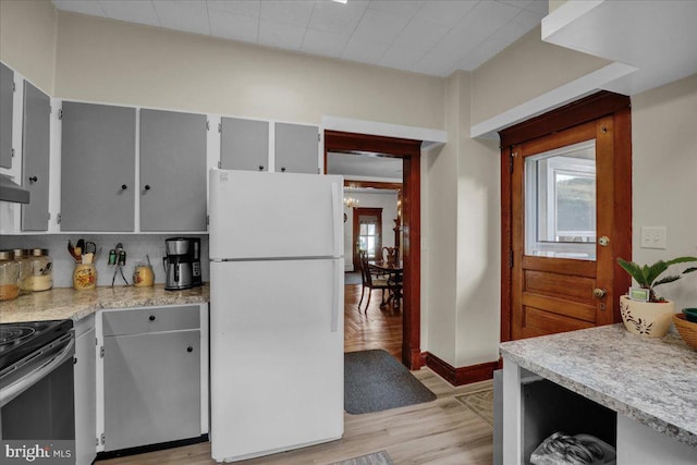 kitchen featuring light hardwood / wood-style floors, white fridge, gray cabinetry, decorative backsplash, and stainless steel range with electric stovetop