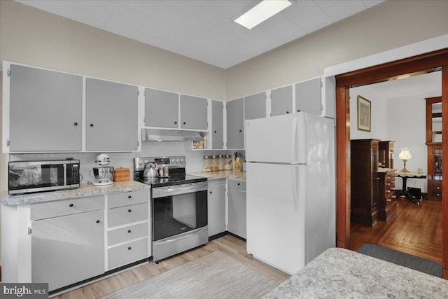 kitchen with gray cabinetry, light hardwood / wood-style floors, appliances with stainless steel finishes, and tasteful backsplash