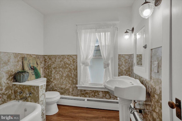 bathroom featuring a bath, wood-type flooring, toilet, and a baseboard radiator