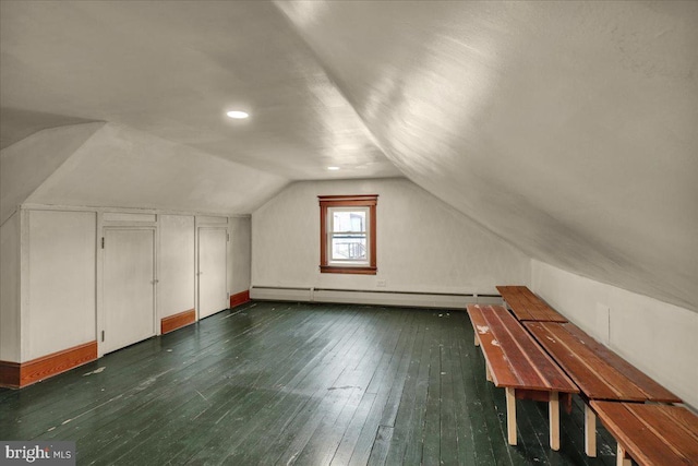 additional living space with baseboard heating, vaulted ceiling, and dark hardwood / wood-style flooring