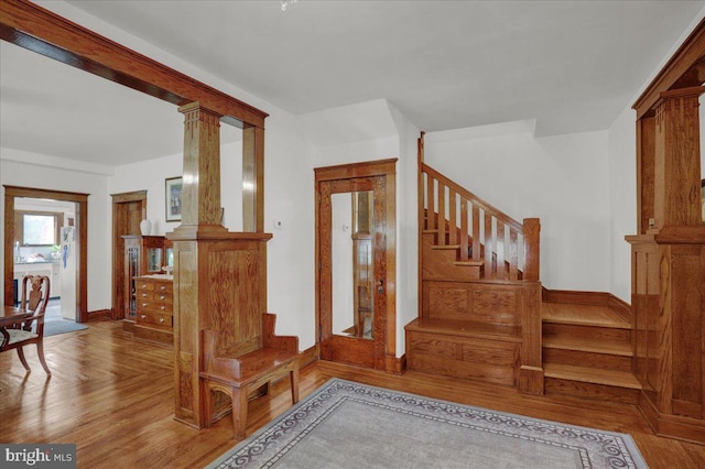 staircase featuring hardwood / wood-style flooring and ornate columns