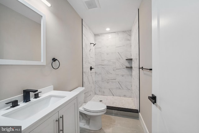 bathroom featuring vanity, tile patterned flooring, toilet, and tiled shower