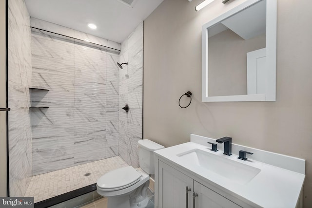 bathroom with tiled shower, vanity, and toilet