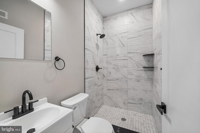 bathroom with tiled shower, vanity, and toilet