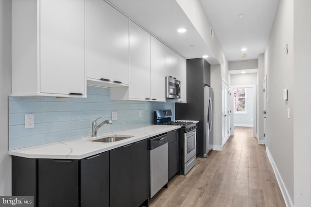 kitchen with light hardwood / wood-style floors, sink, white cabinets, appliances with stainless steel finishes, and light stone countertops