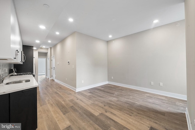 kitchen with light hardwood / wood-style floors, sink, decorative backsplash, and white cabinetry