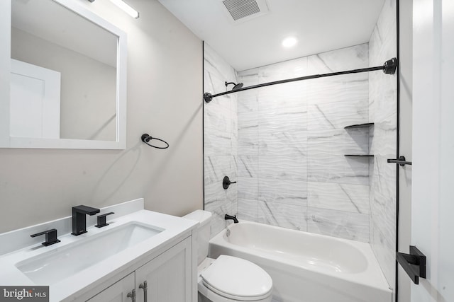 full bathroom featuring vanity, tiled shower / bath, and toilet