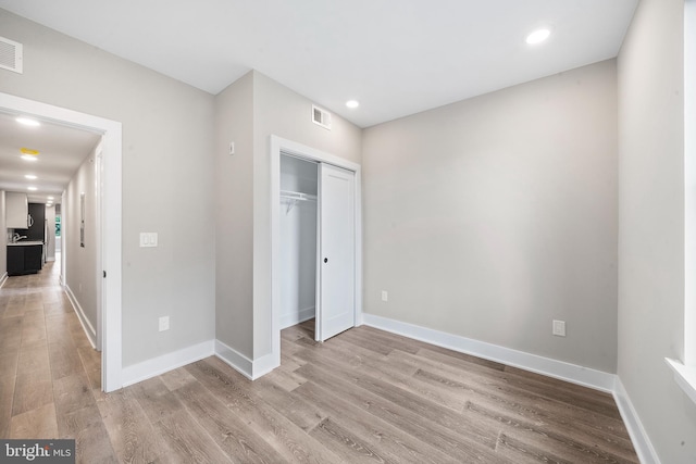 unfurnished bedroom with light hardwood / wood-style flooring and a closet