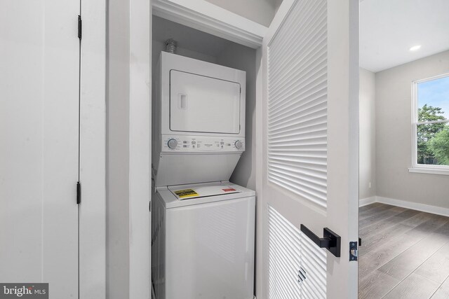 washroom featuring light wood-type flooring and stacked washer and clothes dryer