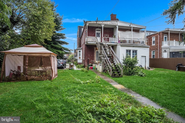 back of house featuring a balcony, a gazebo, and a yard