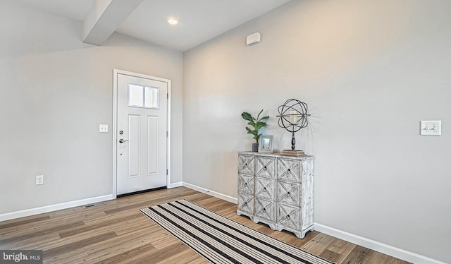 foyer entrance featuring beamed ceiling and wood-type flooring