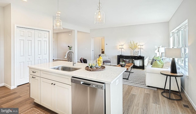 kitchen featuring white cabinetry, dishwasher, sink, an island with sink, and hanging light fixtures