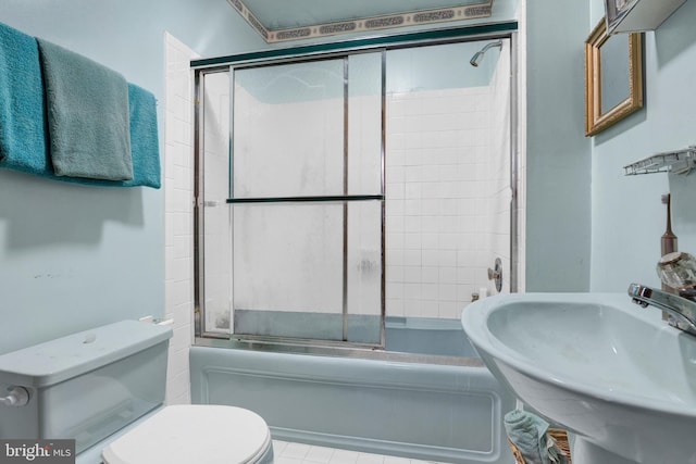 bathroom with a sink, toilet, and bath / shower combo with glass door