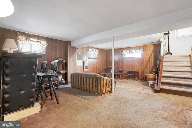 interior space with carpet flooring, wooden walls, and stairs