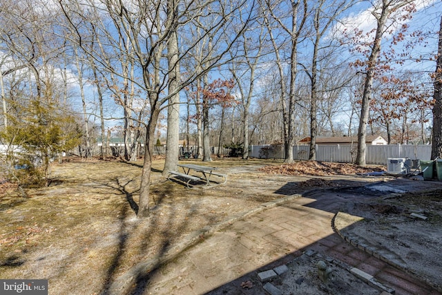 view of yard with central AC and fence