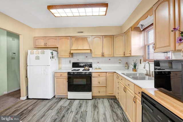 kitchen with black dishwasher, range, freestanding refrigerator, custom exhaust hood, and light brown cabinetry