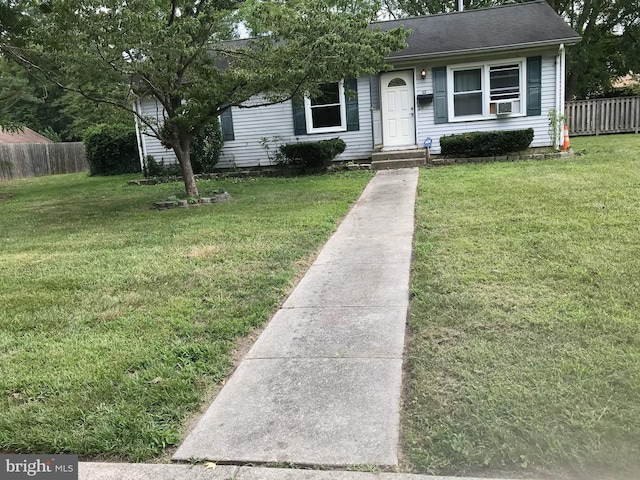 view of front of home with roof with shingles, fence, and a front yard