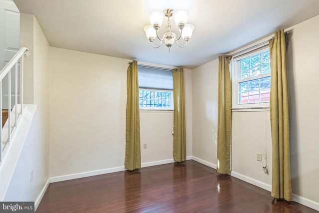 spare room with dark hardwood / wood-style floors, a chandelier, and a wealth of natural light