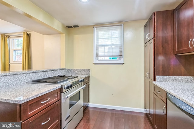 kitchen with stainless steel appliances, light stone countertops, dark wood-type flooring, and plenty of natural light