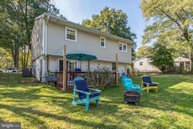 back of property featuring a deck, a lawn, and an outdoor fire pit