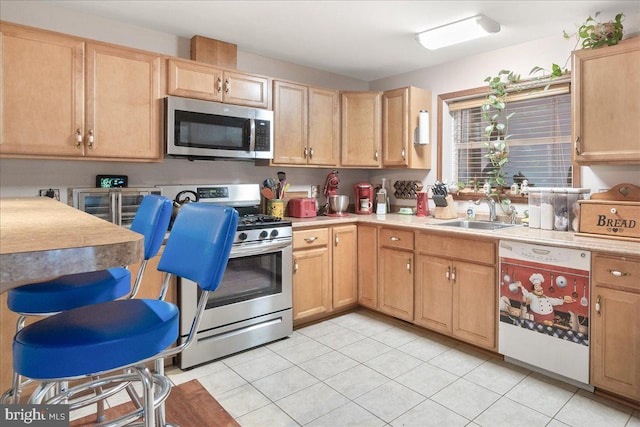 kitchen with light brown cabinetry, light tile patterned flooring, sink, and stainless steel appliances