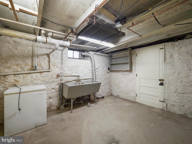 basement featuring white refrigerator and sink