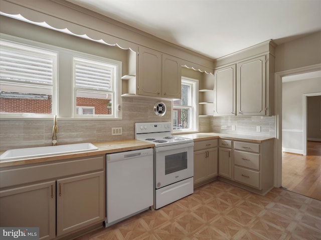 kitchen with light parquet flooring, backsplash, white appliances, cream cabinets, and sink