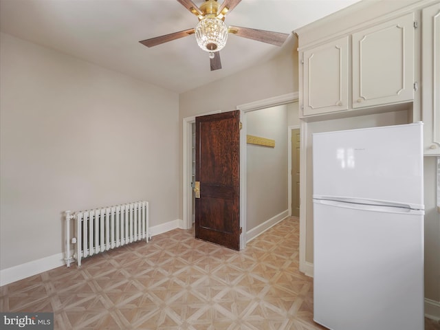 kitchen with white cabinetry, white refrigerator, radiator heating unit, light parquet floors, and ceiling fan