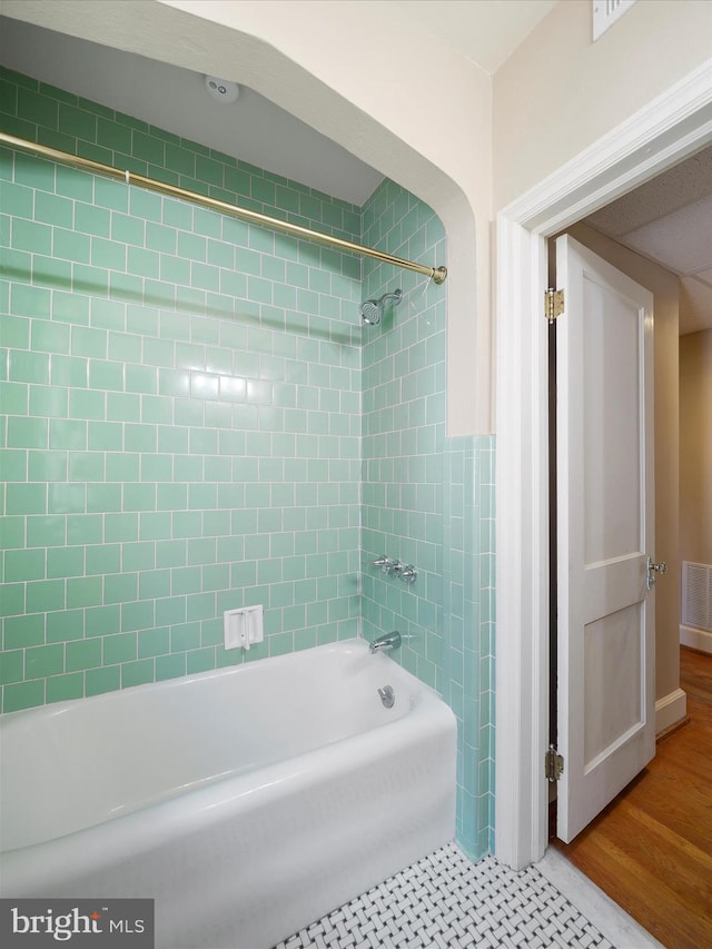 bathroom with tiled shower / bath combo and hardwood / wood-style floors