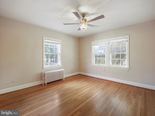 spare room featuring radiator, ceiling fan, and light hardwood / wood-style flooring