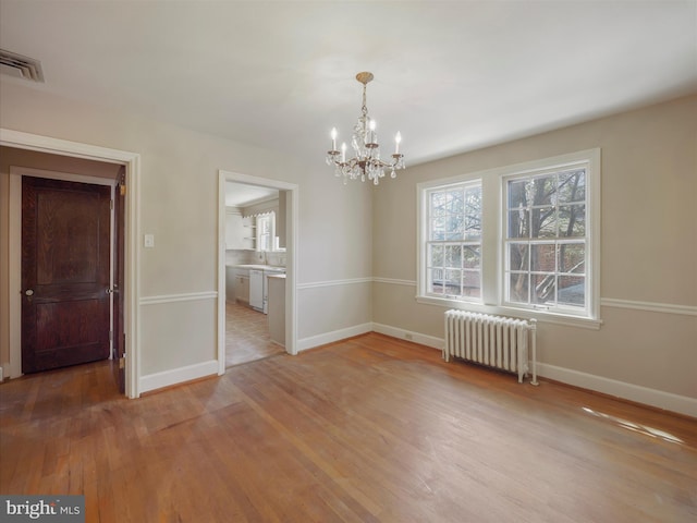 spare room featuring radiator heating unit, light hardwood / wood-style flooring, an inviting chandelier, and sink