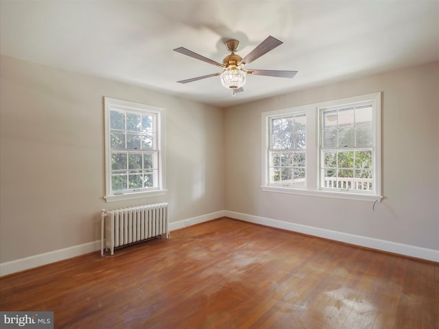 unfurnished room with ceiling fan, radiator heating unit, and hardwood / wood-style flooring