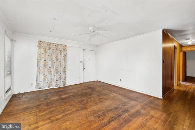 unfurnished room featuring wooden walls, ceiling fan, and dark wood-type flooring