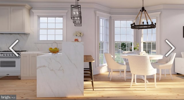 dining room with light hardwood / wood-style floors, ornamental molding, and a chandelier