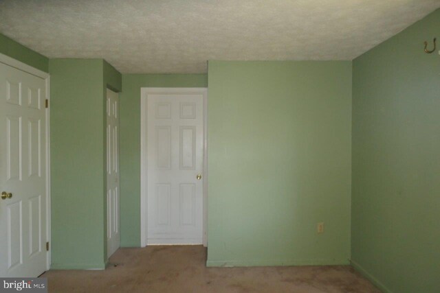 unfurnished bedroom featuring a textured ceiling and light colored carpet