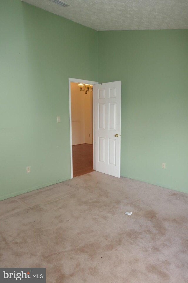 carpeted empty room featuring a textured ceiling